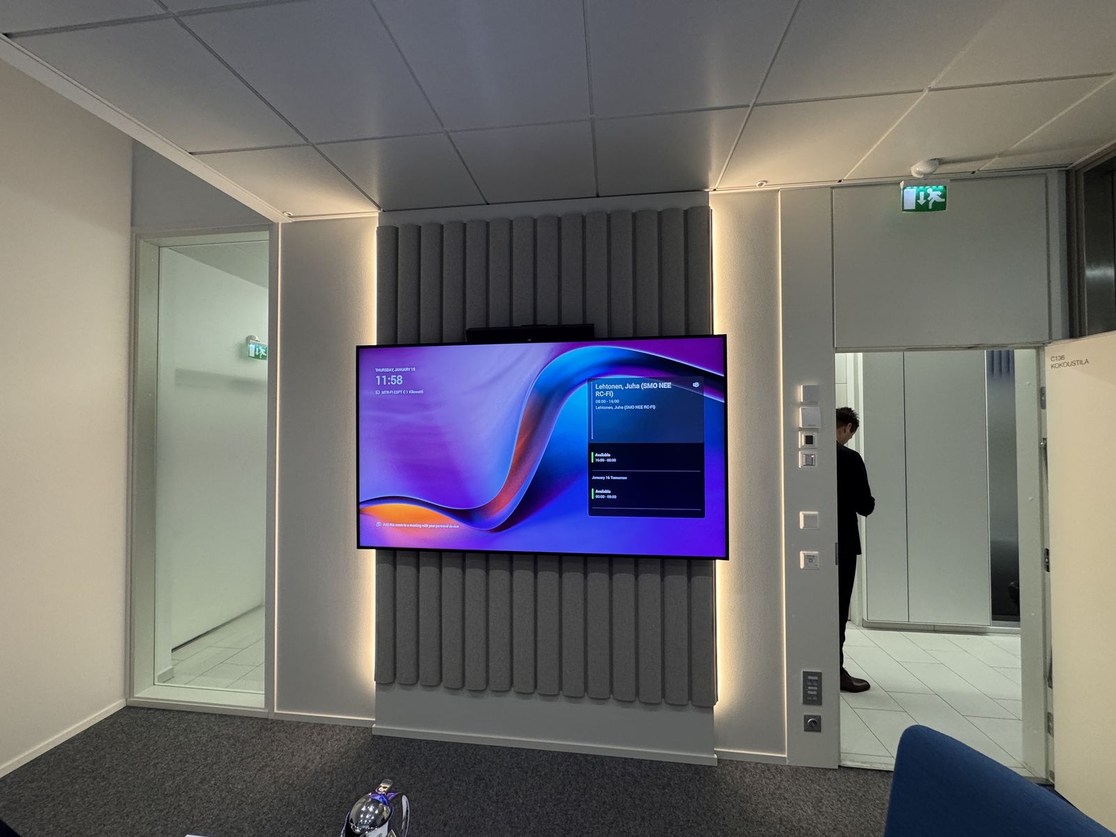 Wandabsorber in Lamellenoptik hinter dem Display eines Meetingraums