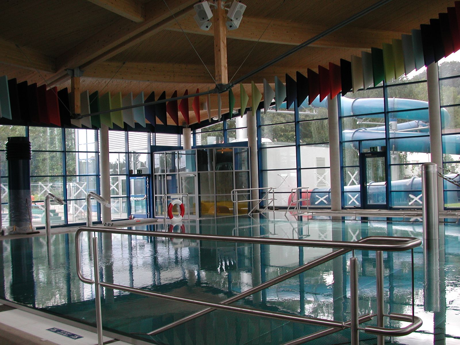 Farbige Baffeln über dem Beckenumgang einer Schwimmhalle