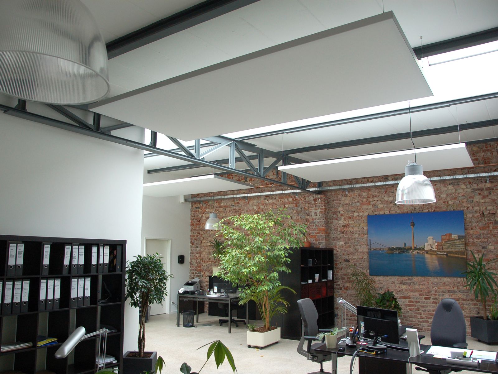 Weißes Akustik-Deckensegel über einem Büro mit Backsteinwand