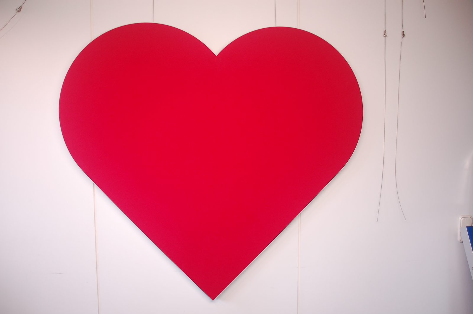 Roter Wandabsorber in Herzform an einer hellen Wand