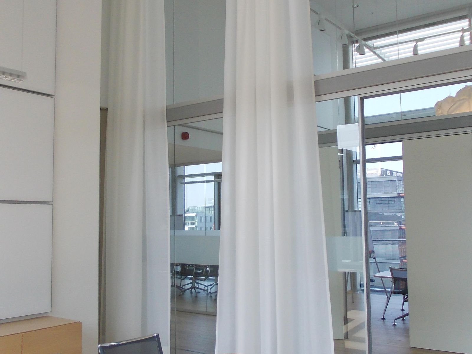 Transparenter Akustikvorhang als Raumteiler vor der Fensterfront eines Besprechungsraums